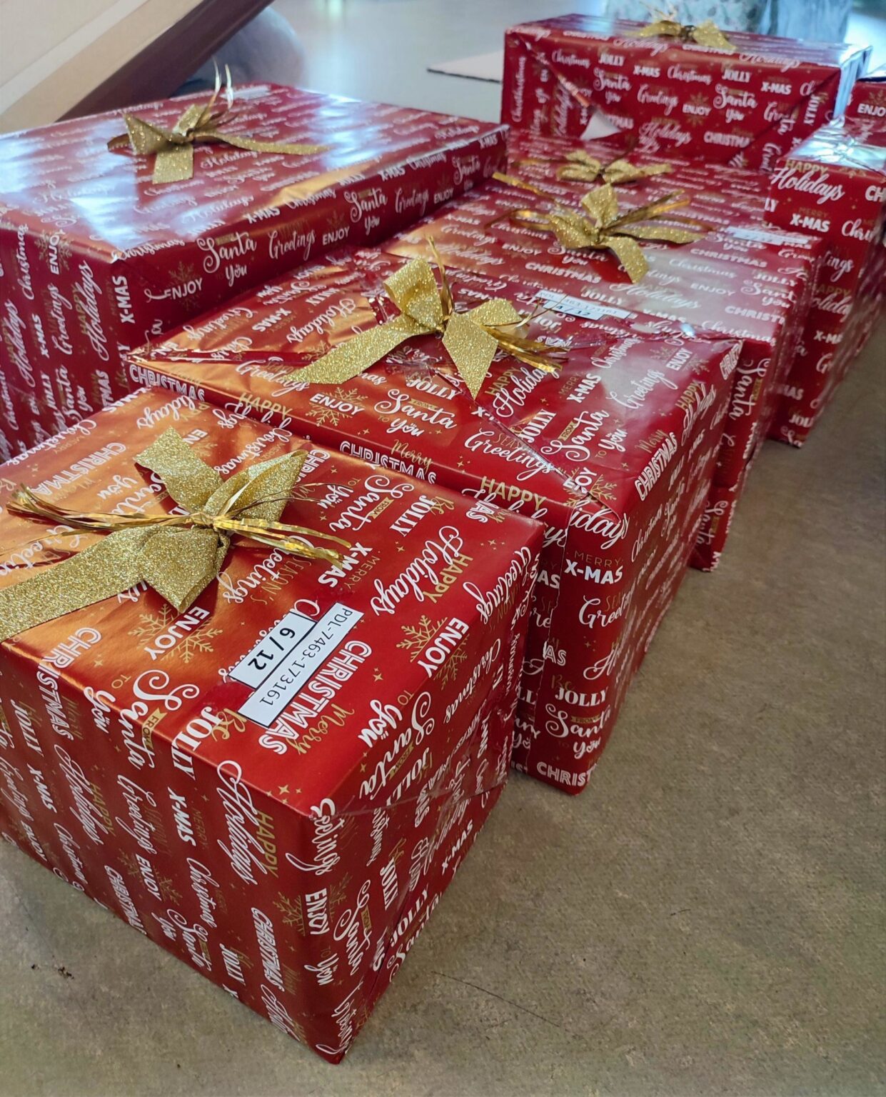 Zapakowanie w czerwony świąteczny papier prezenty dla Szlachetna paczki z złotymi kokardami.