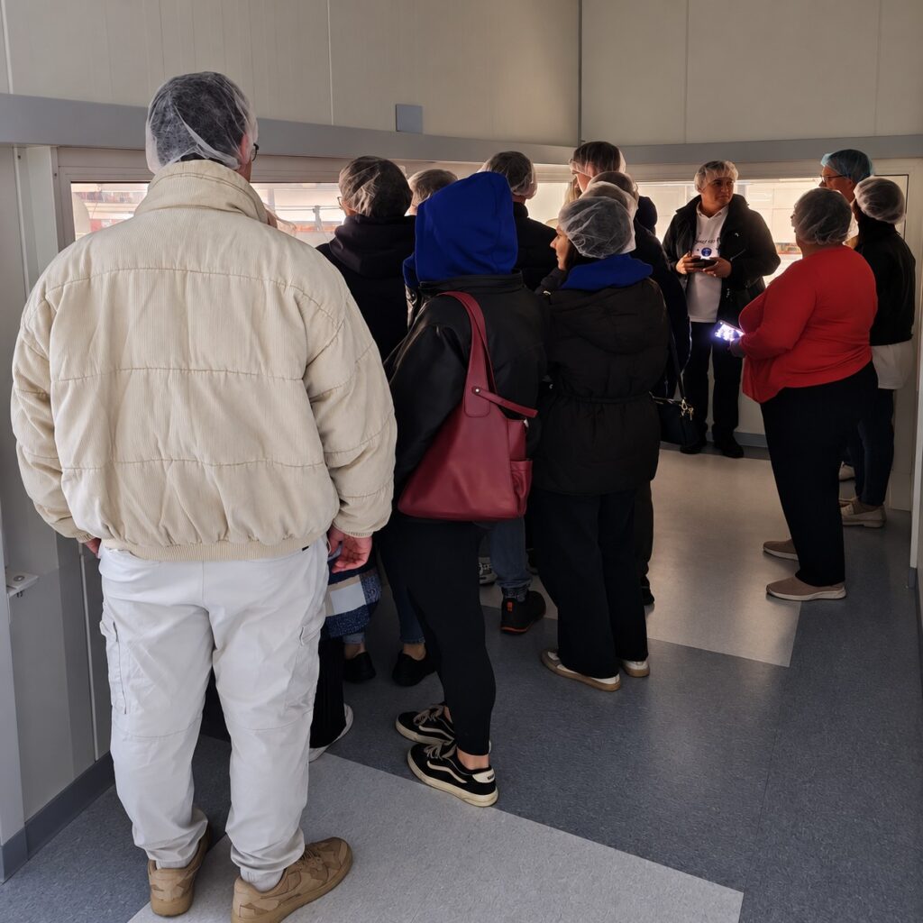 Students from the University of Agribusiness in Łomża, from Slovakia and Ukraine, during their visit to TMT. Wearing protective hairnets, the participants observe the production hall from above, learning about the organization and operation of manufacturing processes.